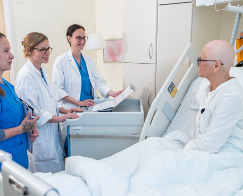 3 Frauen stehen am Bett einer Patientin